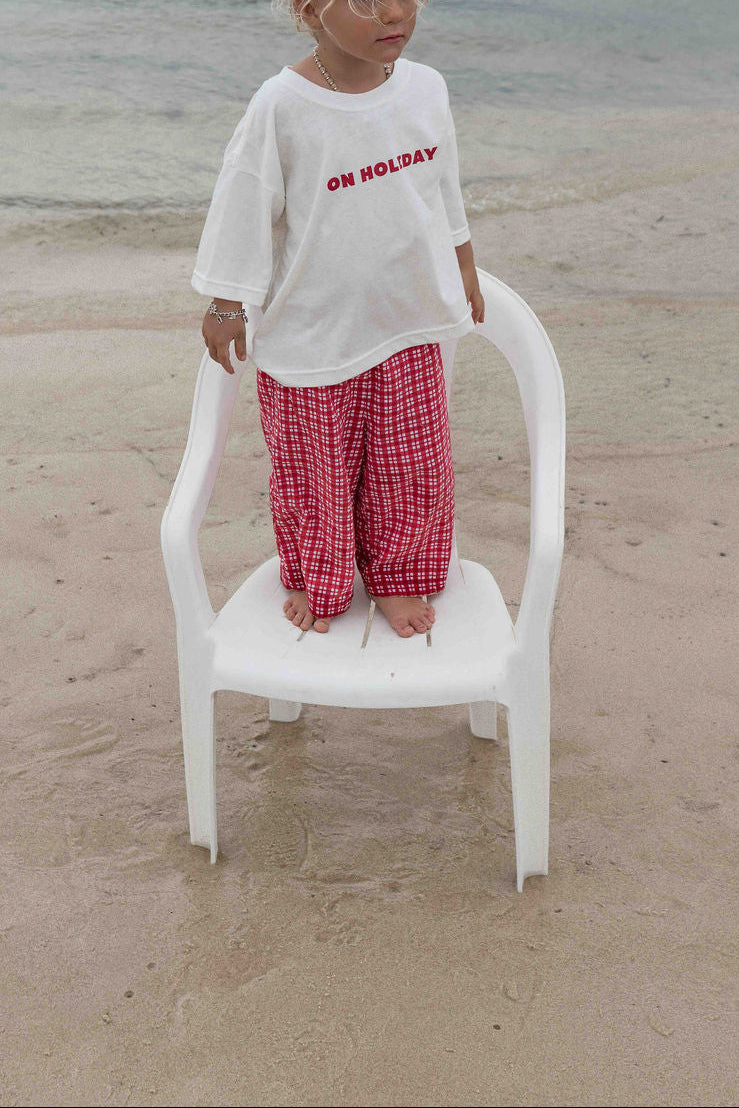 Children's t-shirt made from soft 100% orgaic cotton in a off white oversized fit with red ‘ON HOLIDAY’ graphic. The shirt has a relaxed, comfy fit.