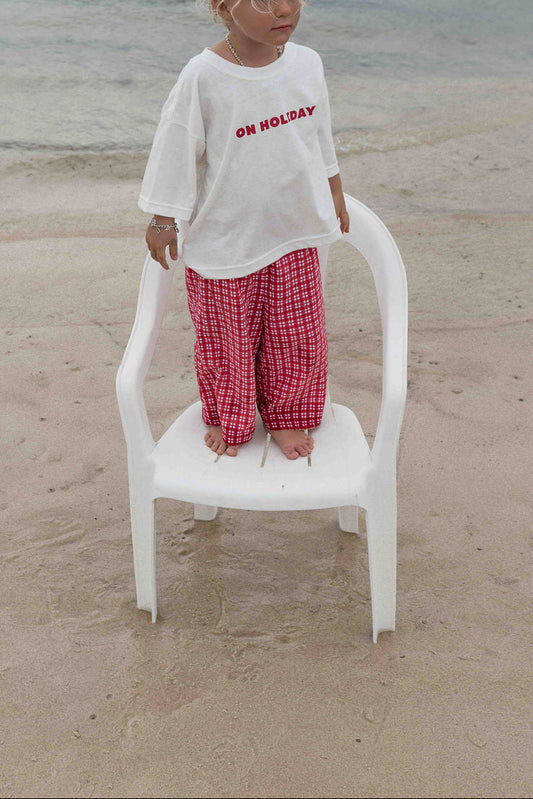 Children's t-shirt made from soft 100% orgaic cotton in a off white oversized fit with red ‘ON HOLIDAY’ graphic. The shirt has a relaxed, comfy fit.