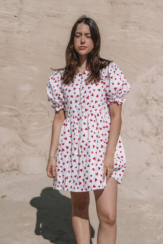 womens mini dress smock in red and white heart print with puff sleeves and adjustable back ties can be worn reversed has a button down front and is breastfeeding friendly
