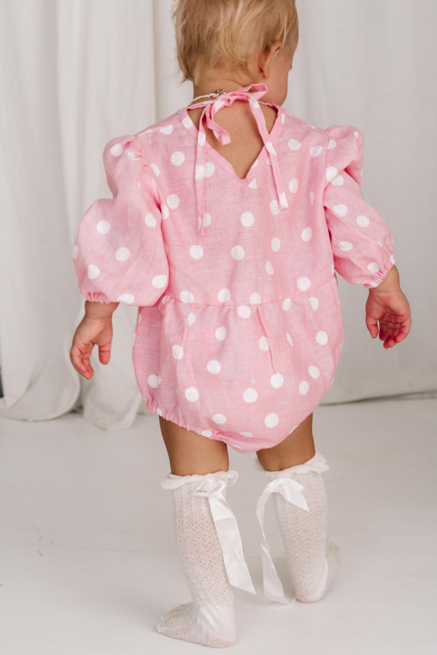 baby toddler romper in the cutest polkadot print hot pink with white dots a v neck front a adjustable back with ties long sleeves with elastic cuffs