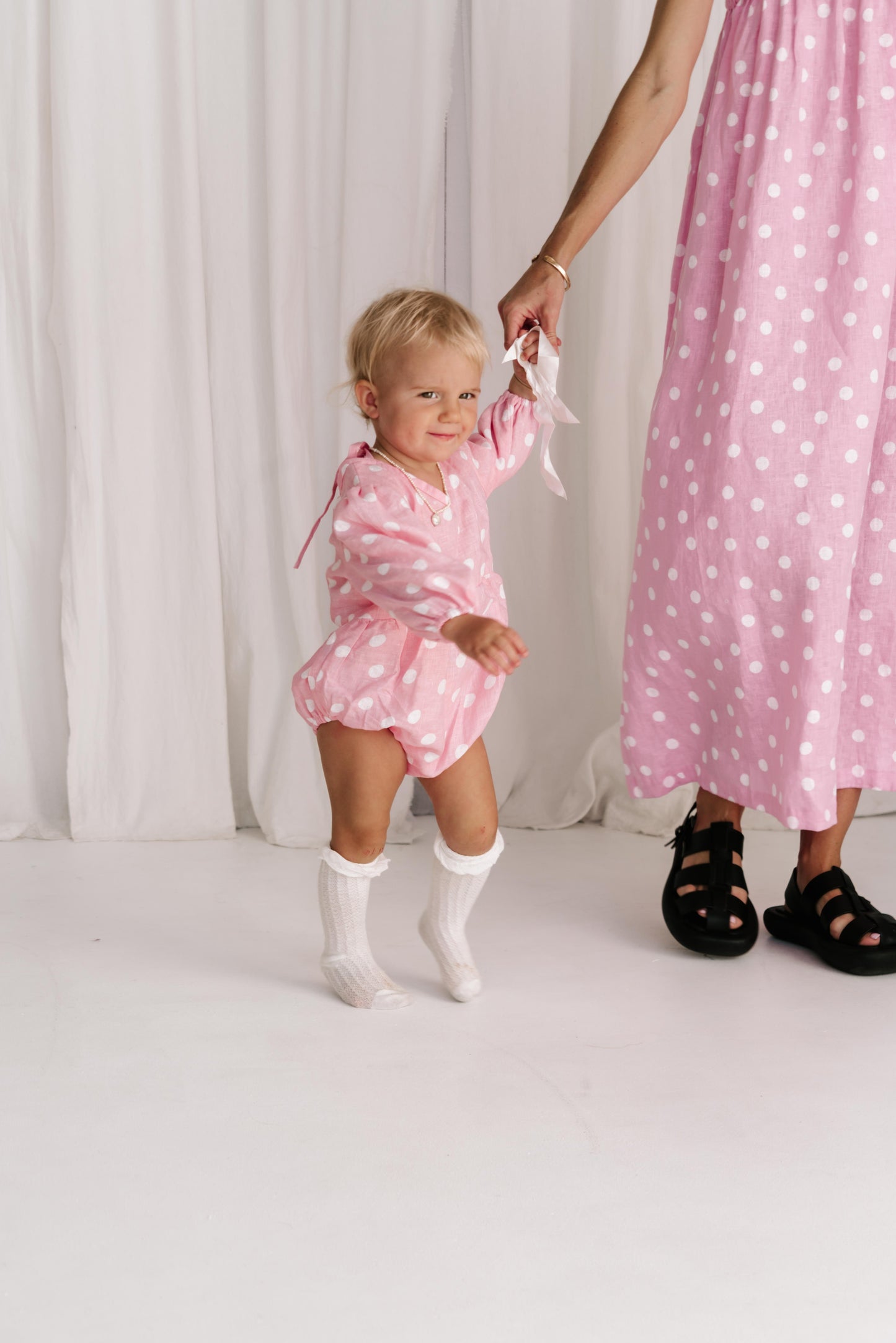 baby toddler romper in the cutest polkadot print hot pink with white dots a v neck front a adjustable back with ties long sleeves with elastic cuffs