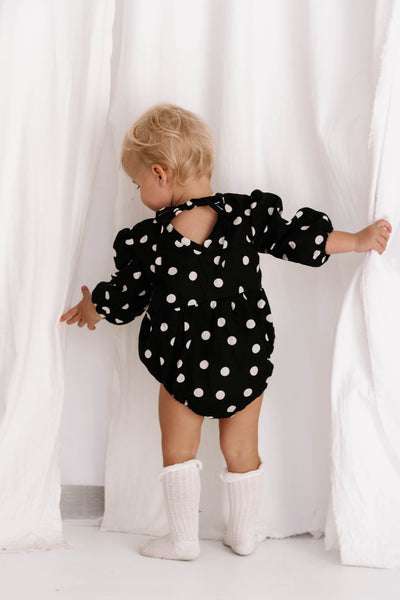 baby toddler romper in the cutest polkadot print in black and white colour with white dots a v neck front a adjustable back with ties long sleeves with elastic cuffs