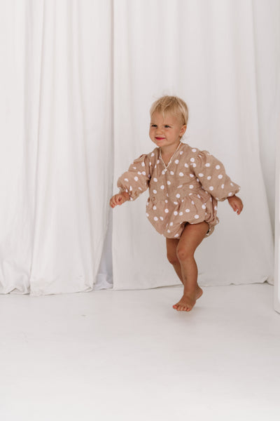 baby toddler romper in the cutest polkadot print nougat beige colour with white dots a v neck front a adjustable back with ties long sleeves with elastic cuffs