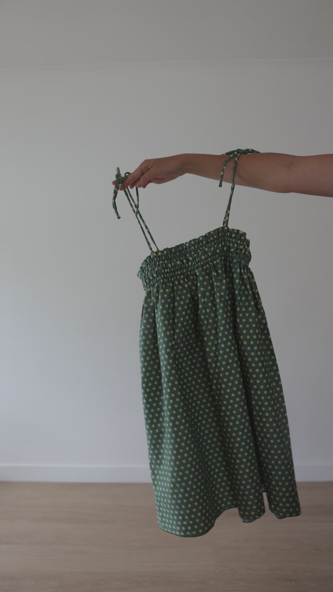 A stunning green mini smock dress with a ruched bust and adjustable spagetti shoulder straps that tie. The fabric is a light weight 100% soft cotton in vibrant green with white yellow polkadots.