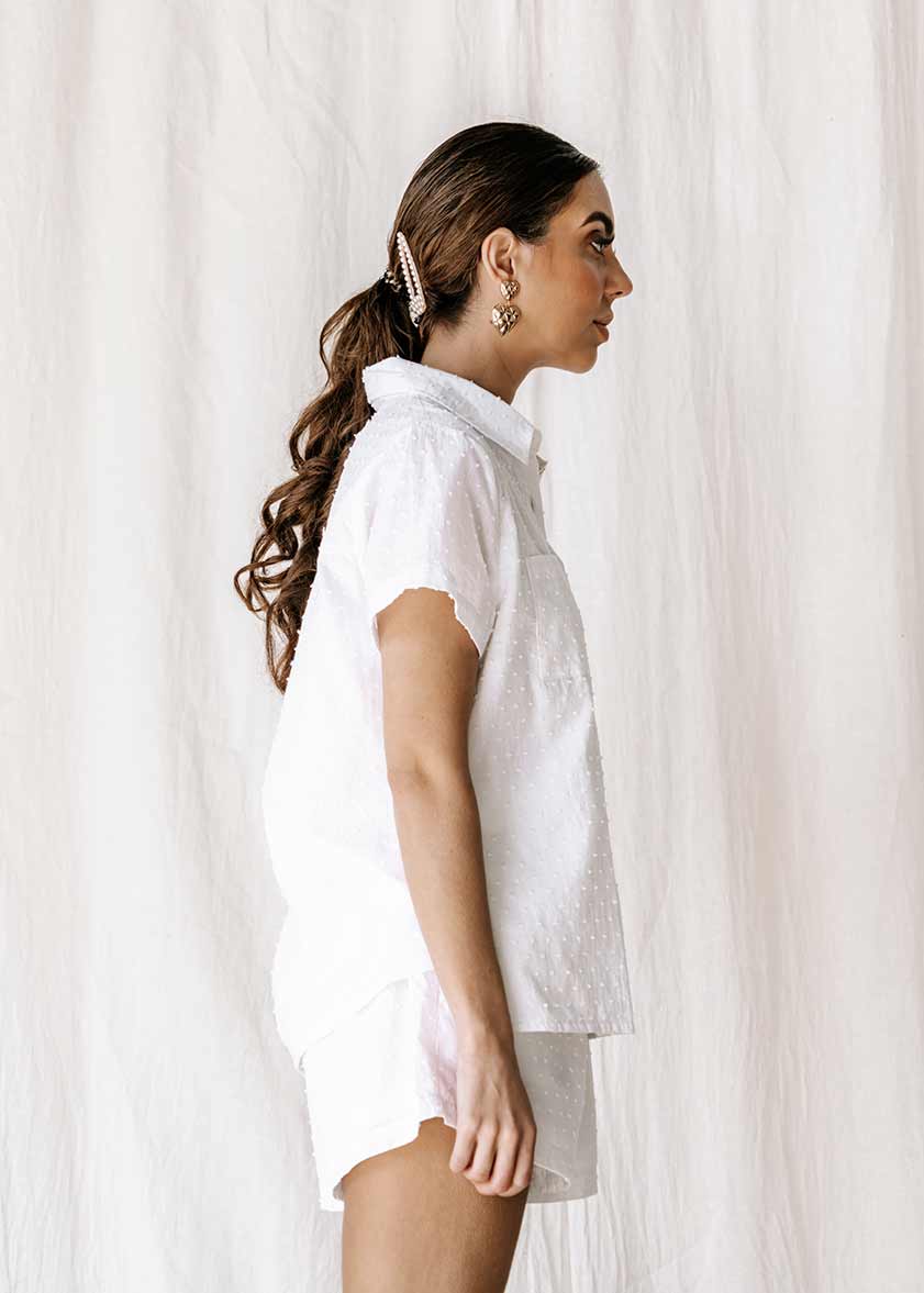 The new everyday blouse that will take you from sunrise to sunset.  The new everyday blouse that will take you from sunrise to sunset, the Capri Shirt is so comfortable you’ll never want to take it off. Button up white textured blouse / shirt, short sleeve super soft. Shell button detail 100% high-quality cotton Beautiful textured dot fabric Pockets Split detail on sides Oversized fit Made from the highest quality cotton fabric, that is cool & breathable to wear  ETHICALLY MADE IN INDONESIA